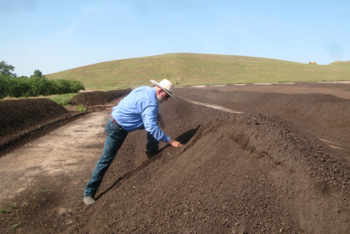 Ward Burroughs inspects compost on Burroughs Family Farms. (Photo courtesy of CalCAN)
